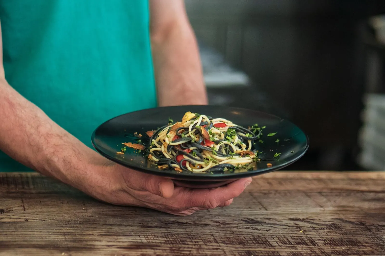 Un plat de spaghetti aux herbes et tomates cerises, apporté en salle