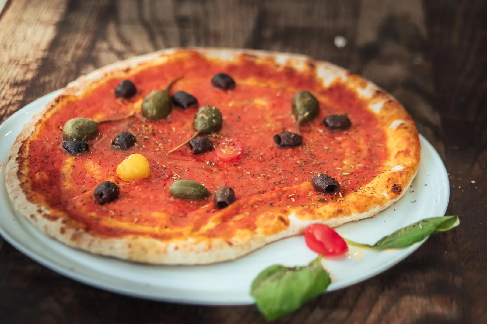 Pizza marinara aux olives et câpres sur assiette blanche
